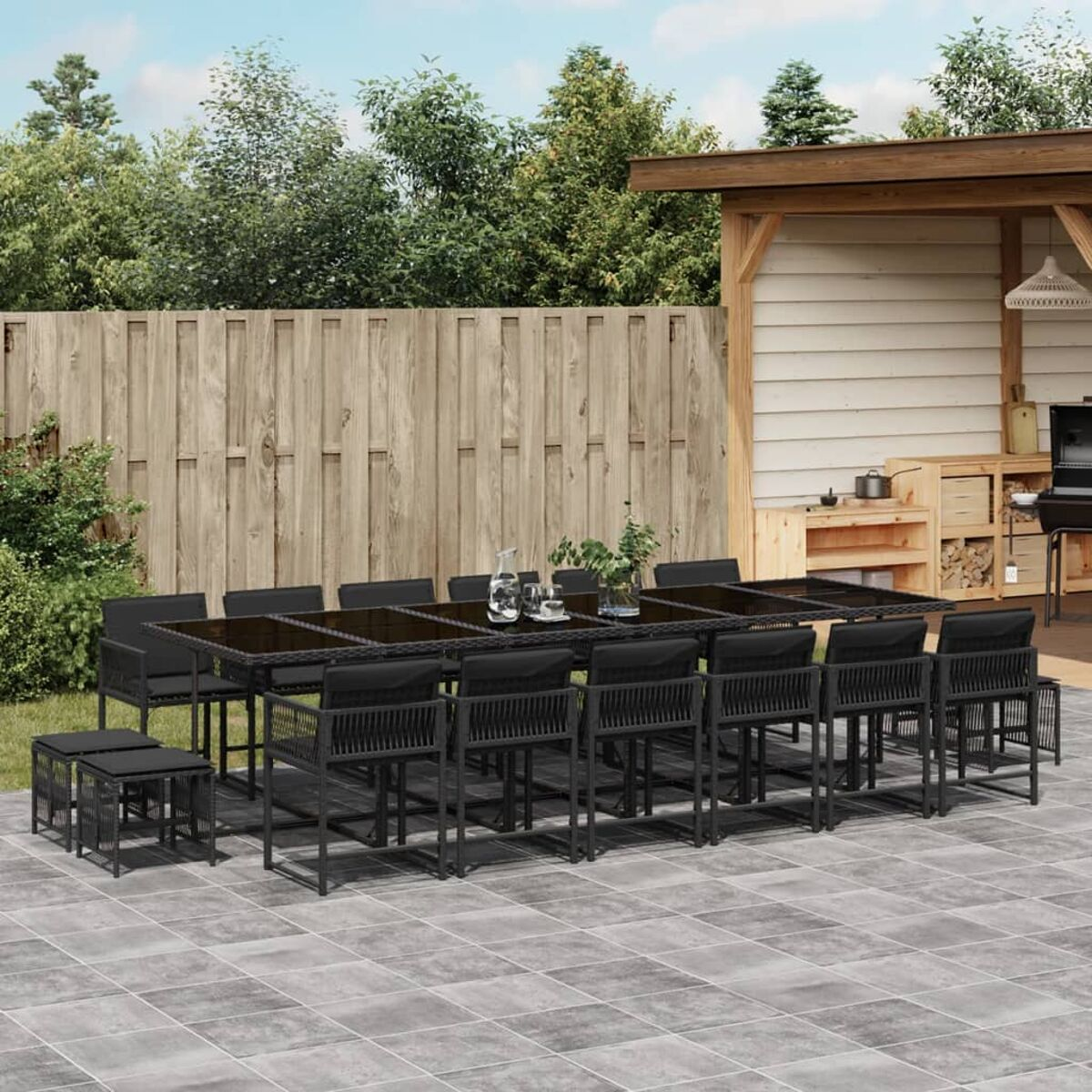 Un juego de patio al aire libre negro con una mesa, sillas y taburetes. El fondo incluye una casa.