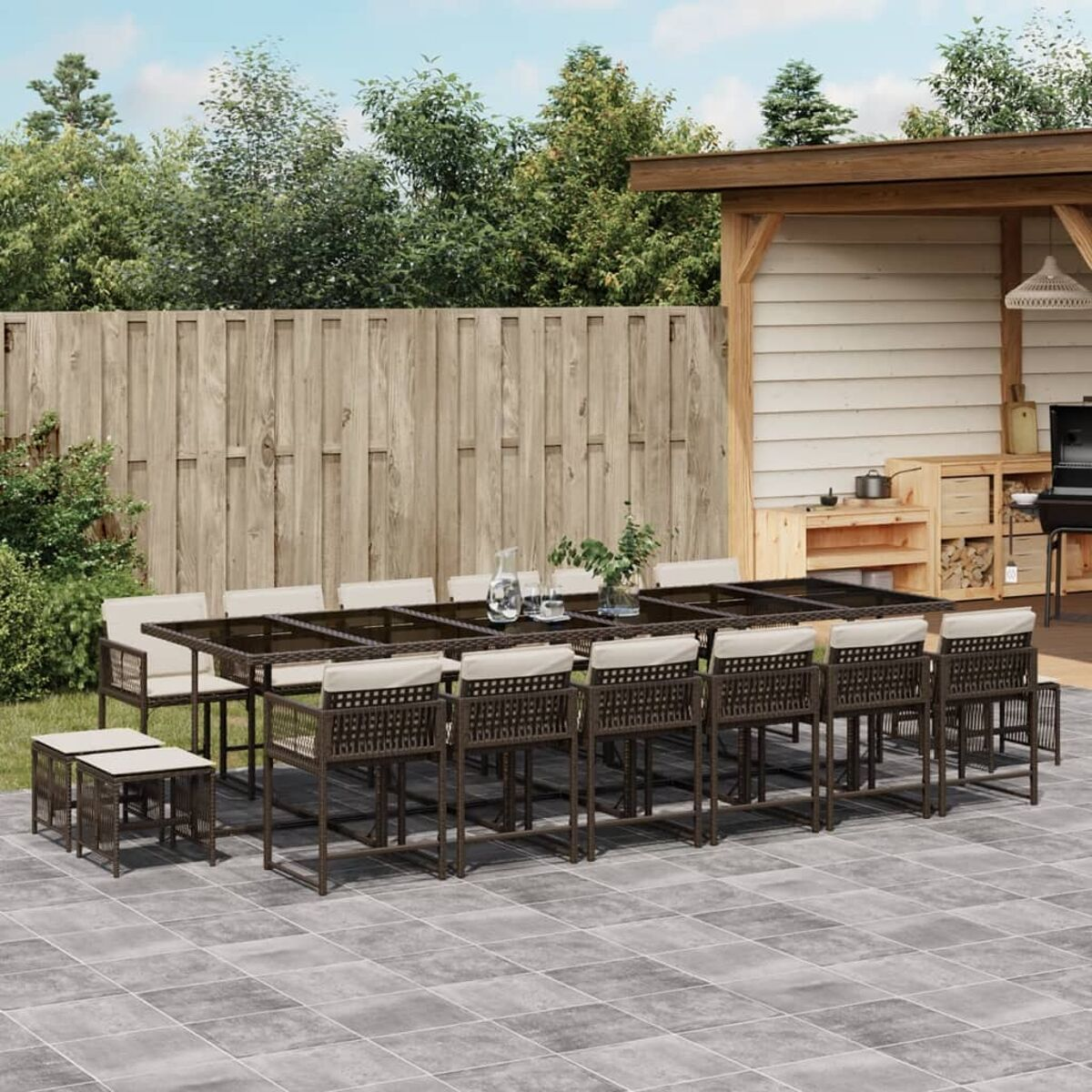 Un set da pranzo all'aperto con un lungo tavolo e sedie. Le sedie hanno cuscini chiari.