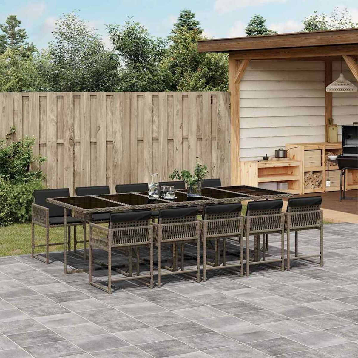 Essgruppe im Freien mit Tisch, Stühlen und dunklen Kissen auf einer Terrasse.