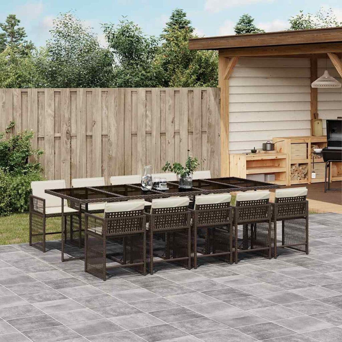 Set da pranzo all'aperto. Sedie con struttura marrone, cuscini bianchi, recinzione in legno.
