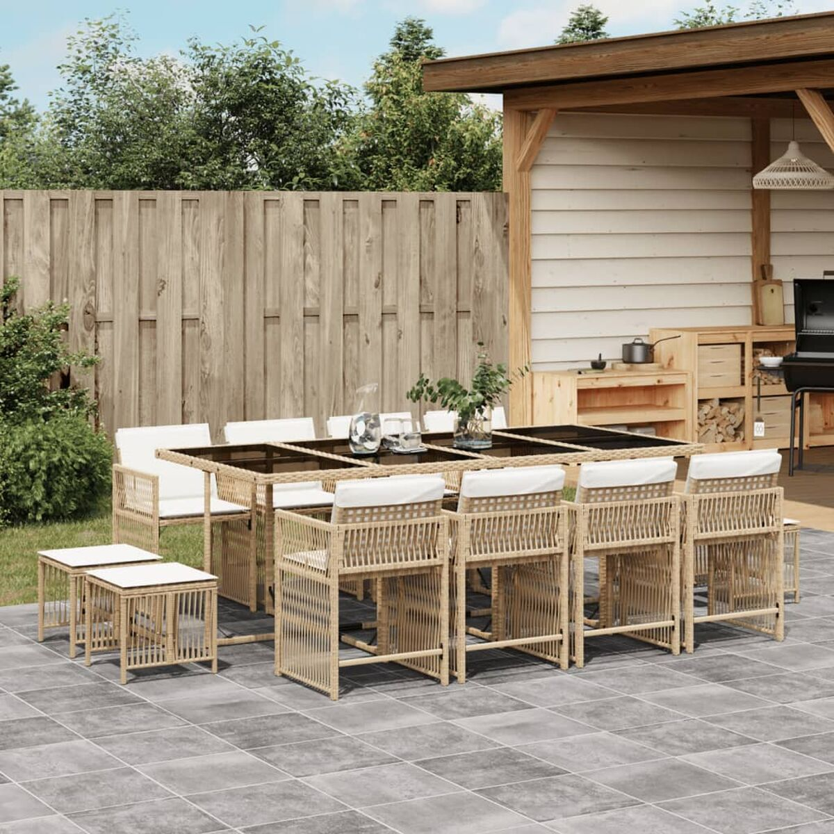 Set da pranzo all'aperto con tavolo e sedie su un patio piastrellato. Recinzione in legno e verde sullo sfondo.