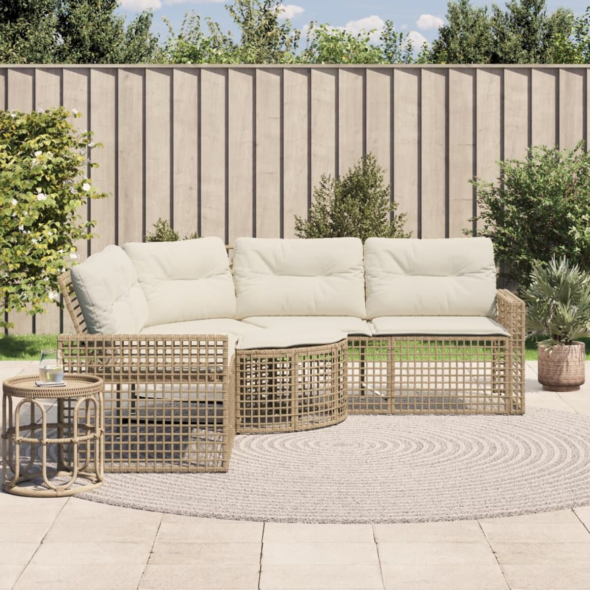Divano componibile da esterno con cuscini beige, struttura in vimini e tavolino rotondo su un patio.