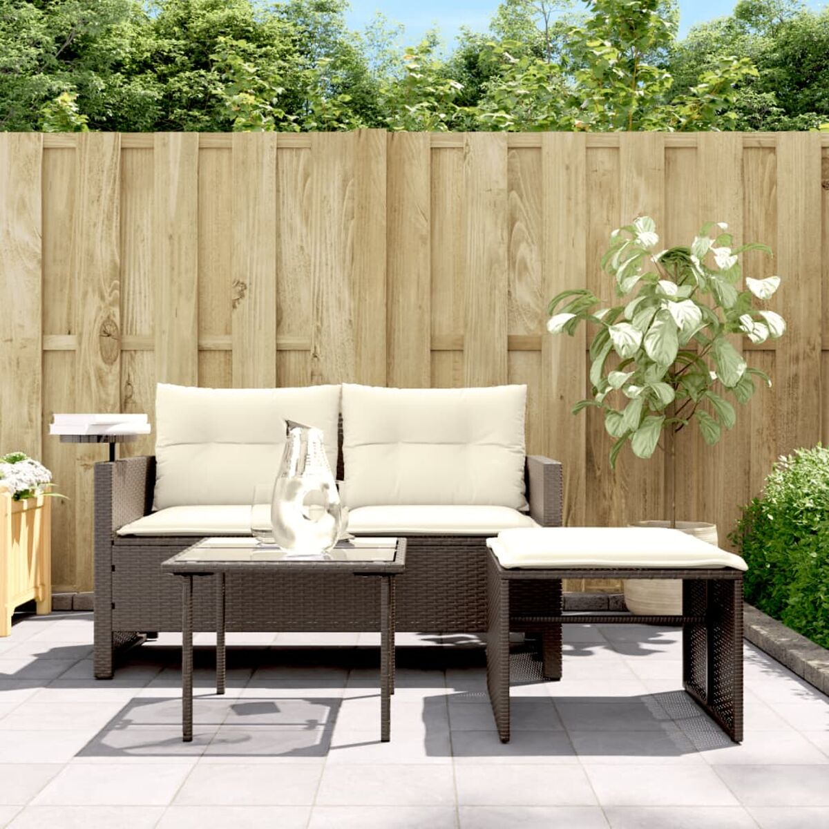 Wicker-Terrassenset: Sofa, Couchtisch und Ottomanen. Beige Kissen, Holzzaun.
