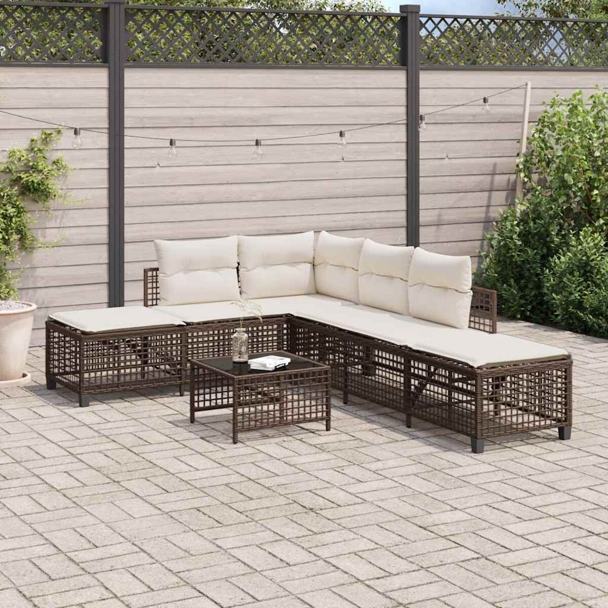 Un divano componibile da esterno in rattan marrone con cuscini color crema e un tavolino.