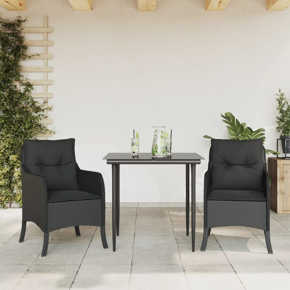 Zwei schwarze Stühle mit Kissen und ein Tisch mit Getränken. Eine weiße Wand im Hintergrund.