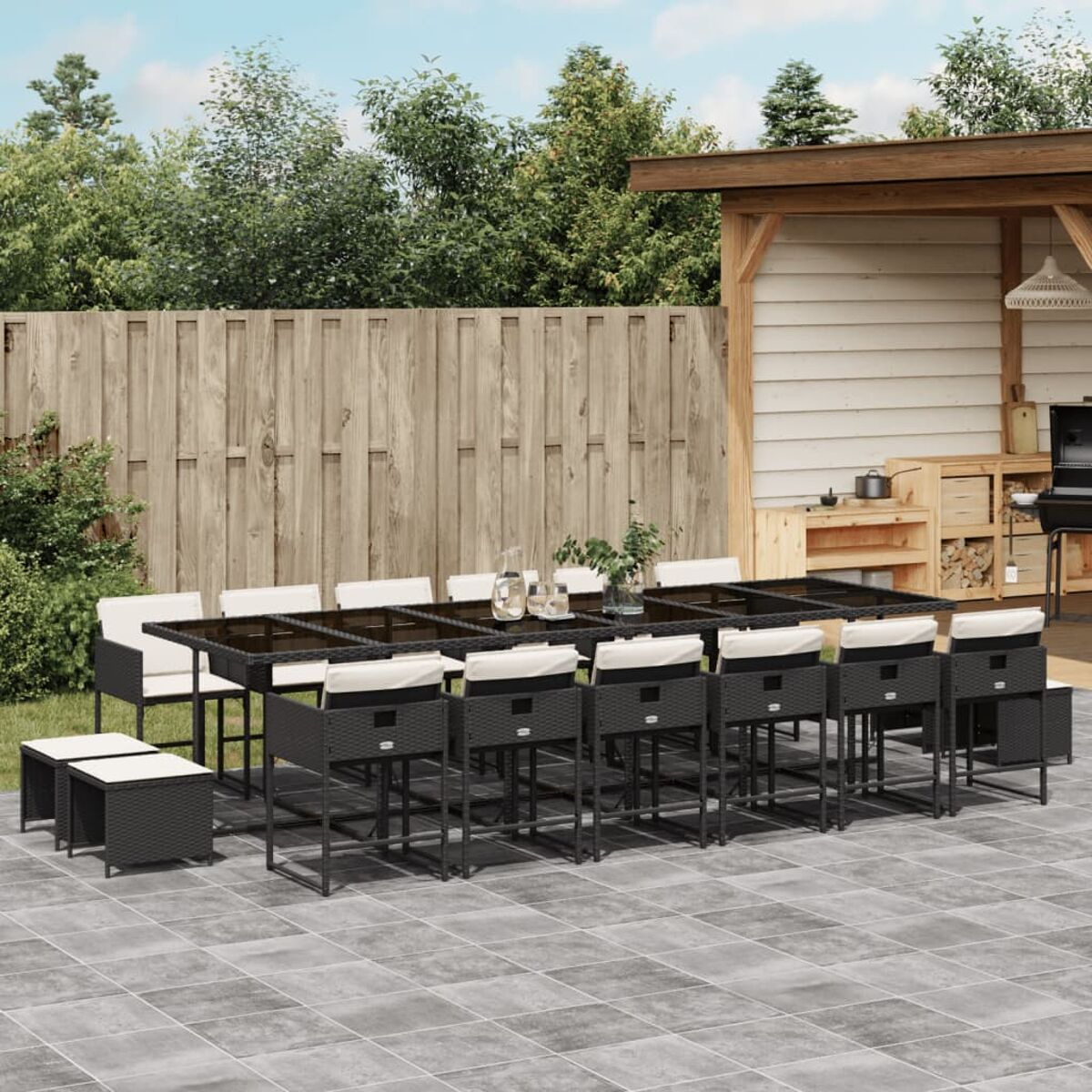 Ess-Set für draußen mit Tisch und Stühlen. Das Set beinhaltet weiße Kissen, Tisch und Hocker. Auf Terrasse.