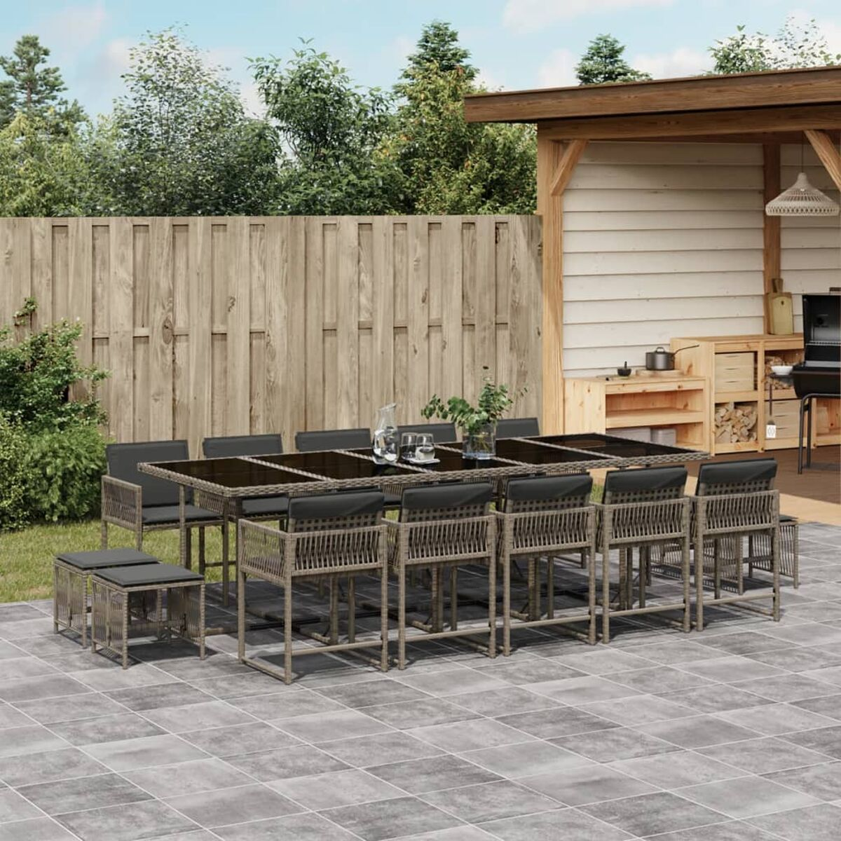 Set da pranzo per esterni con un lungo tavolo e sedie con cuscini grigi su un patio. Include una pergola.