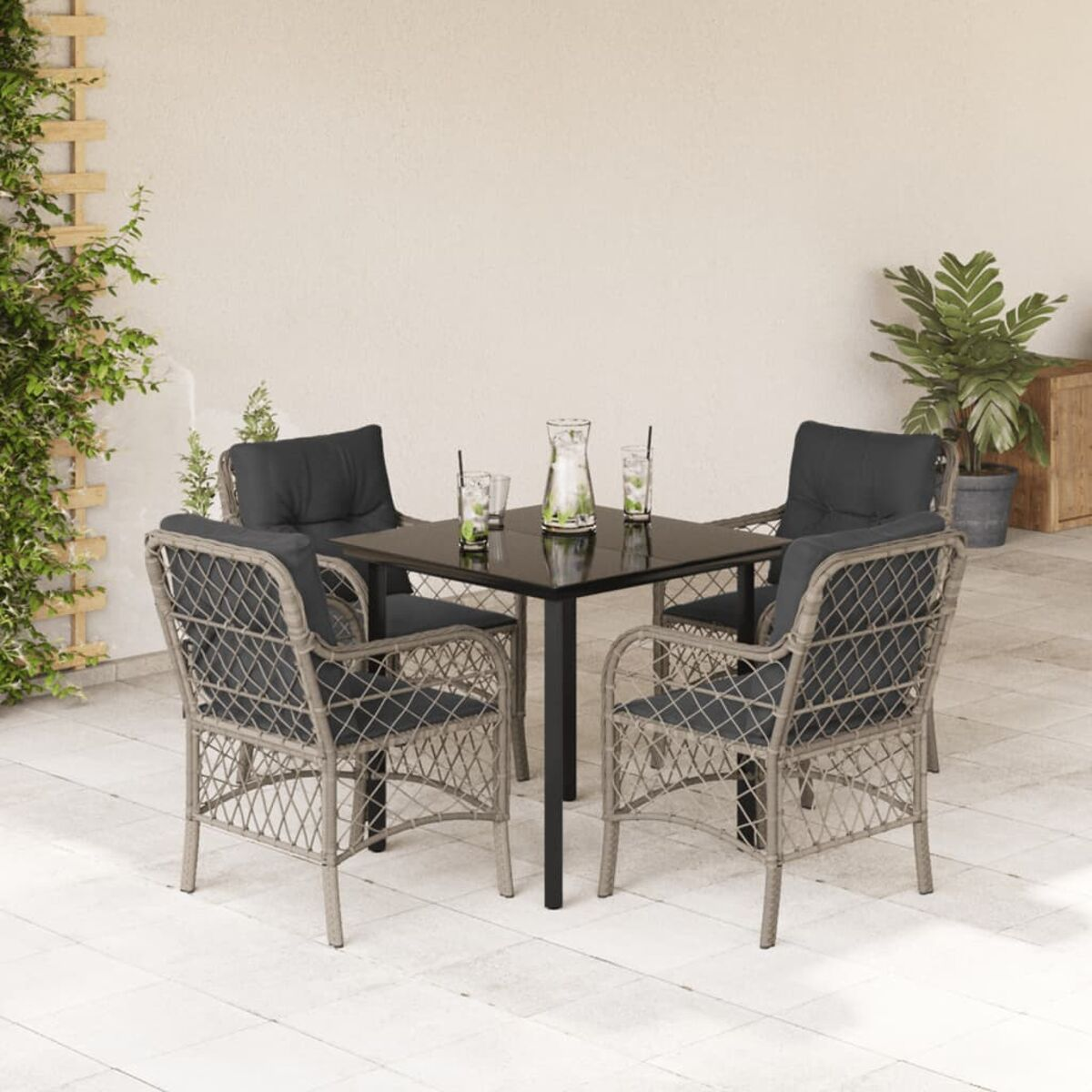 Ein Terrassenset mit Tisch, vier Stühlen und Getränken. Eine weiße Wand und Pflanzen sind im Hintergrund.