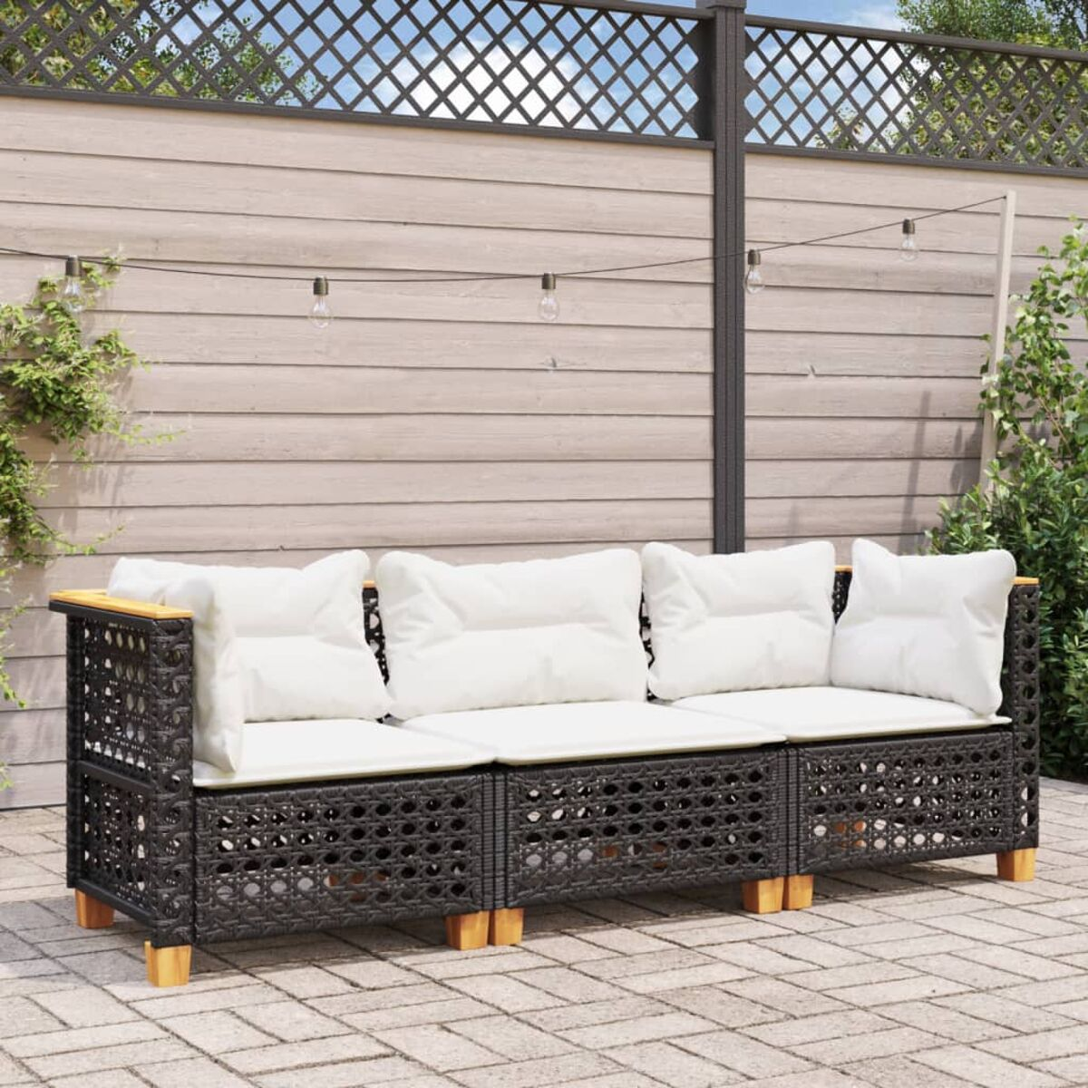 Schwarzes gewebtes Outdoor-Sofa mit weißen Kissen und Holzakzenten, sonniges Setting.