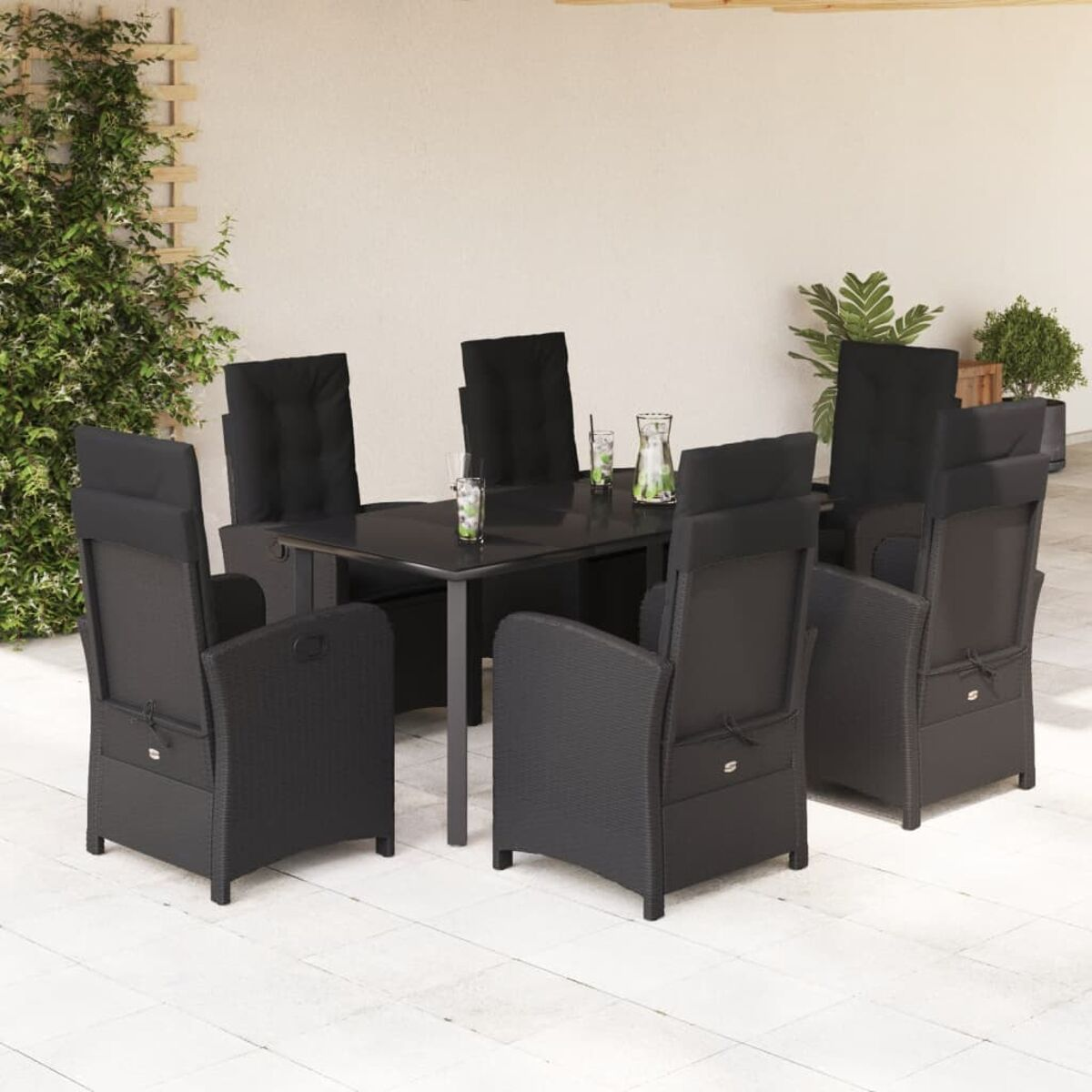 Essgruppe im Freien, schwarze Stühle und Tisch, Pflanzen im Hintergrund.
