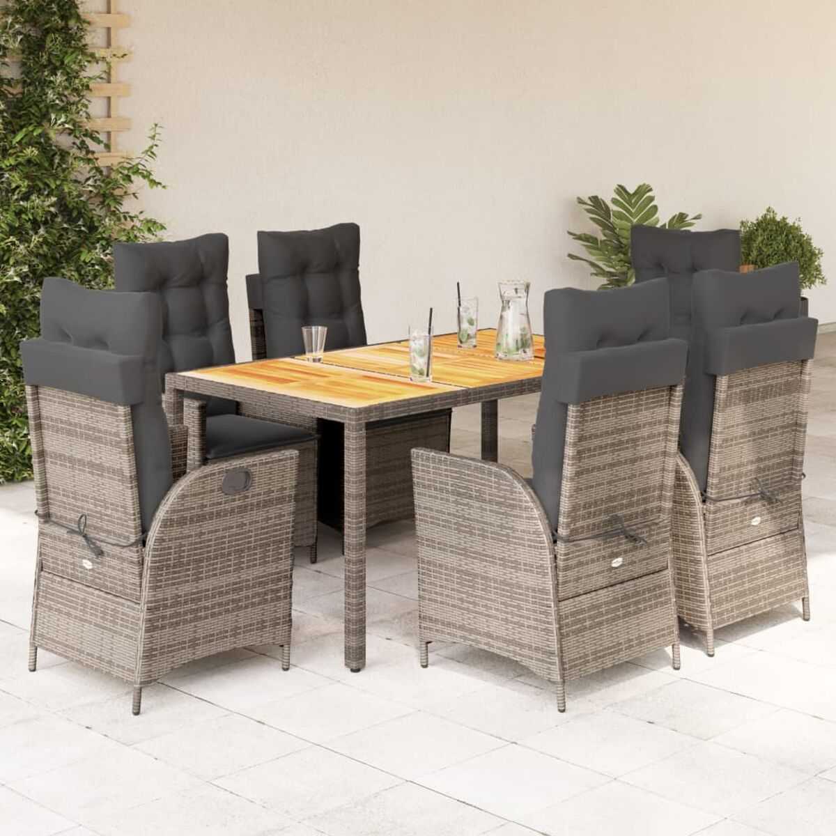 Set da pranzo, sedie in rattan con cuscini grigi, tavolo con piano in legno. Bicchieri sul tavolo.