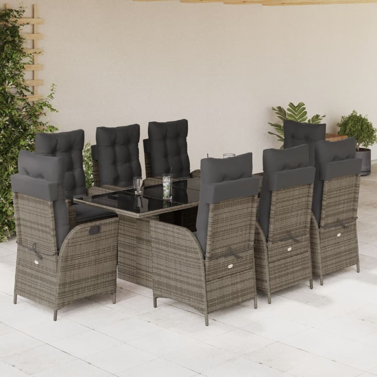 Graue Stühle mit schwarzen Kissen um einen Tisch mit Getränken auf Terrasse.