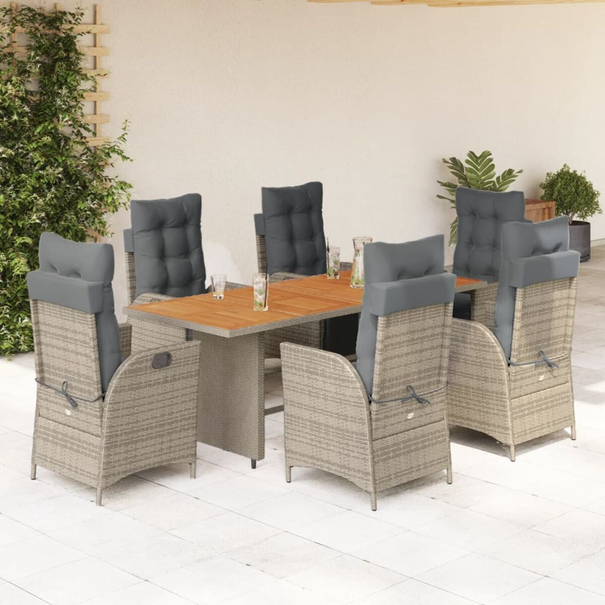 Set da patio: tavolo con sei sedie, cuscini grigi e telai in rattan, su un patio con verde.