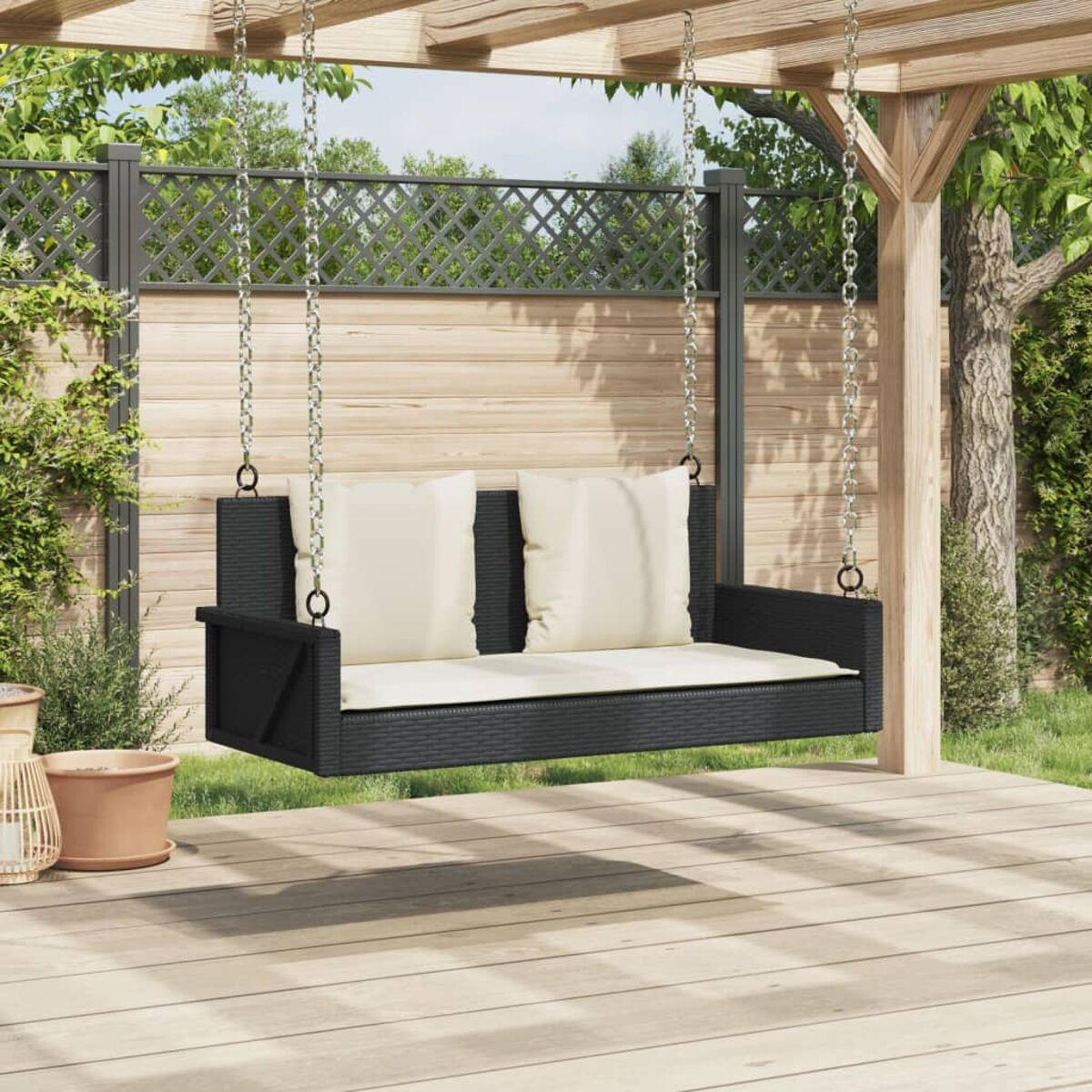 Schwarze Schaukel mit weißen Kissen, die von einer Pergola hängt.