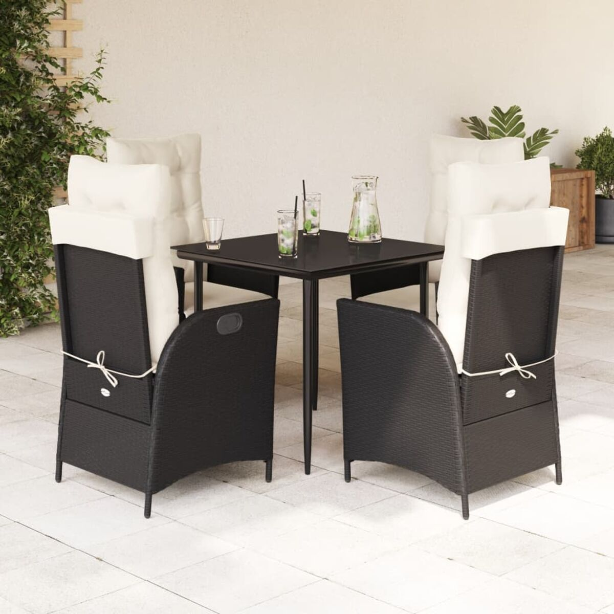 Set da patio esterno con sedie nere, un tavolo nero e cuscini bianchi.