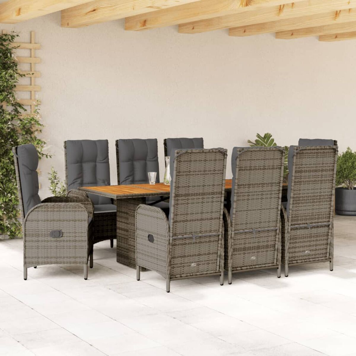 Essgruppe im Freien mit Holztisch und Korbstühlen. Graue Kissen auf Stühlen. Patio-Einstellung.