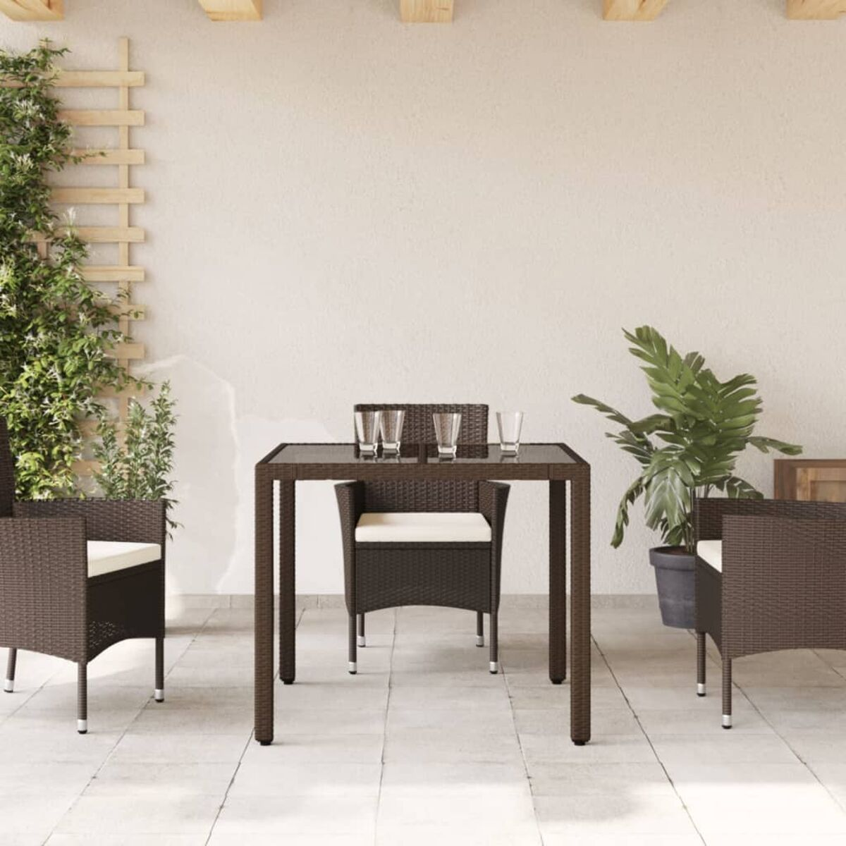 Terrassenset: Tisch, Stühle und Pflanzen. Braune Webmöbel auf einer Terrasse.