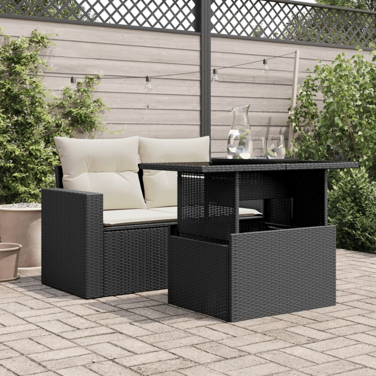 Ein schwarzer Rattan-Tisch mit Hubtisch und zwei Stühlen mit Kissen auf einer Terrasse.