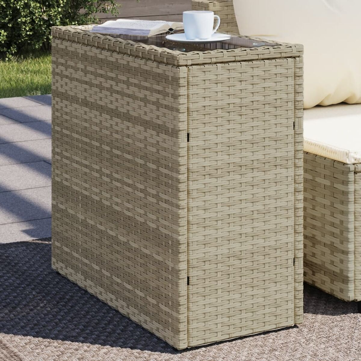 Primo piano di un tavolino in rattan con piano in vetro. Un libro e una tazza sono sul tavolo.