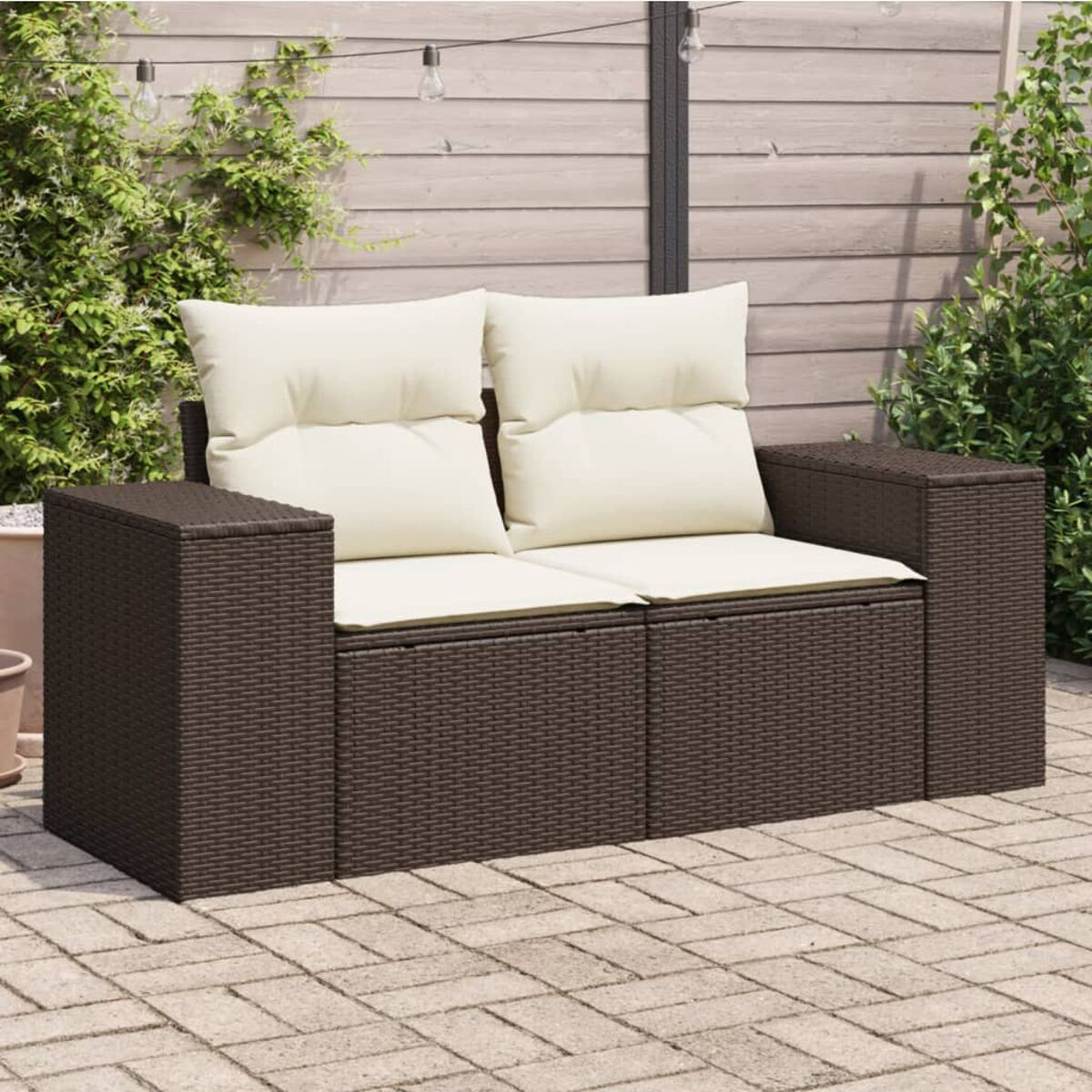 Outdoor-Sofa mit Kissen. Brauner Korbrahmen, auf einer Terrasse, mit Lichterkette.