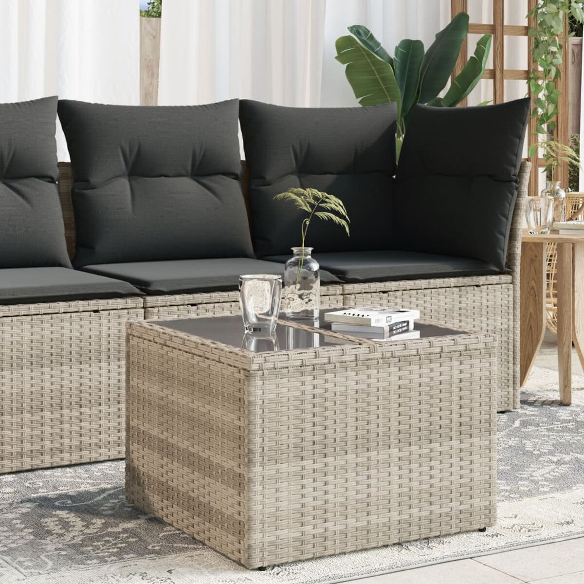 Ein Korbtisch mit Glasplatte. Im Hintergrund ein Sofa und Kissen.
