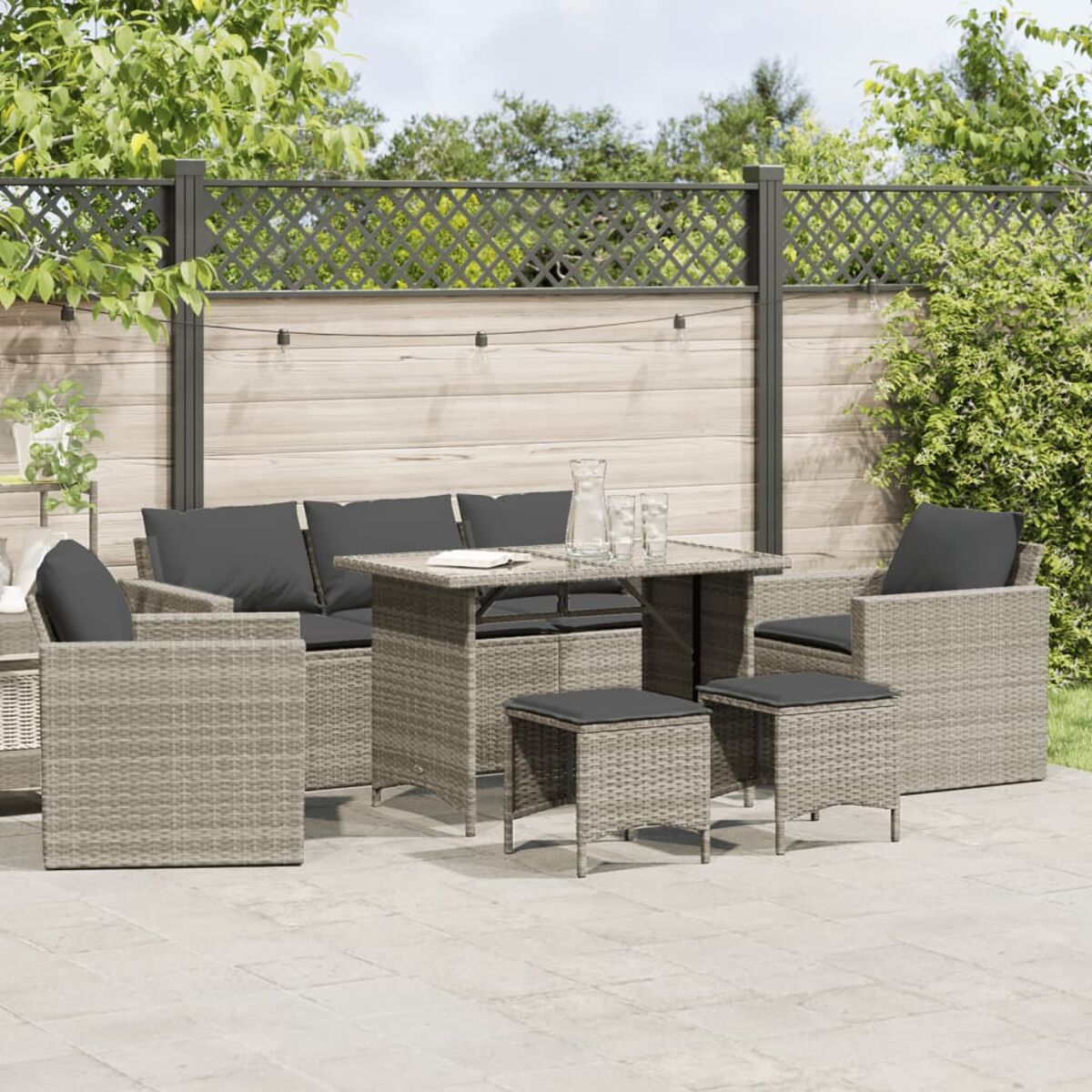Terrassenset mit Tisch, Stühlen und dunkelgrauen Kissen.