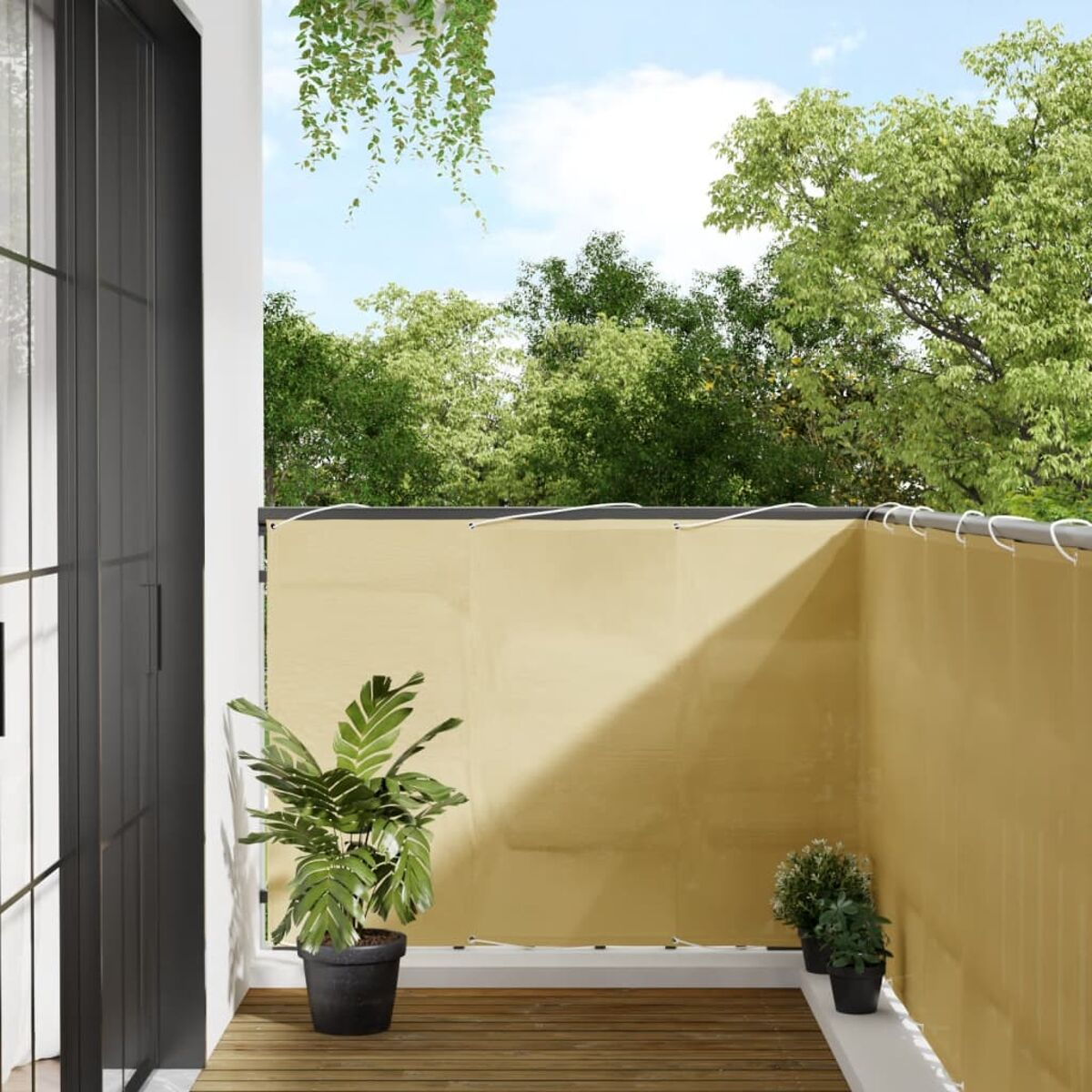 Balkon mit beigem Sichtschutz, einem Topf und Blick auf Bäume und Himmel.