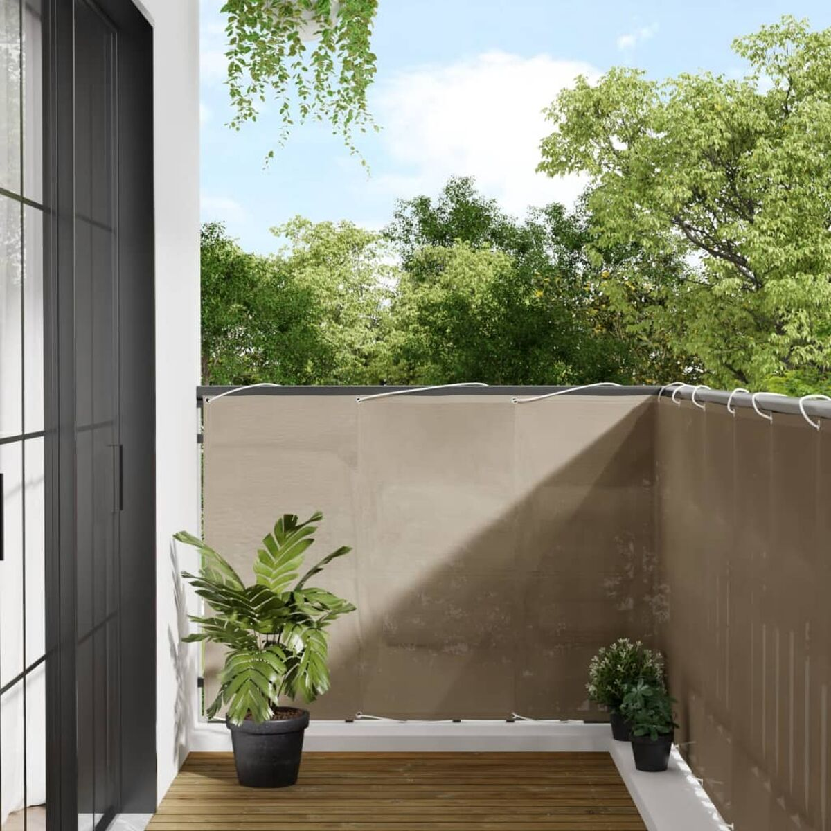 Balkon mit braunem Sichtschutz, Pflanzen und Holzterrasse. Grüne Bäume im Hintergrund.