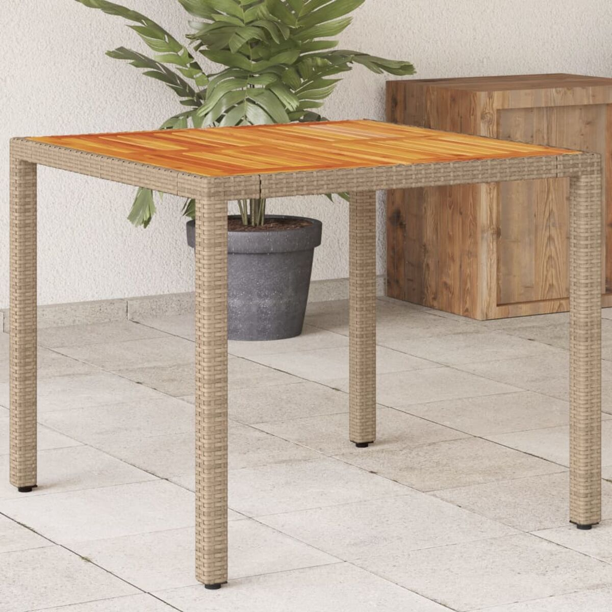Quadratischer Korbtisch mit Holzplatte. Eine Topfpflanze und Holzaufbewahrung im Hintergrund.