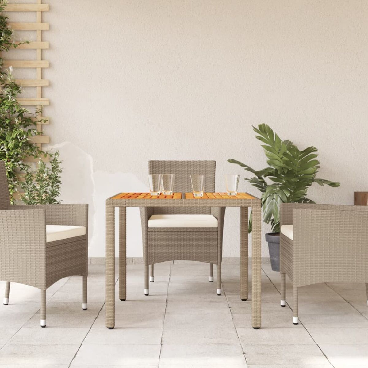 Essgruppe im Freien. Beige geflochtene Stühle und ein Tisch. Pflanzen im Hintergrund.