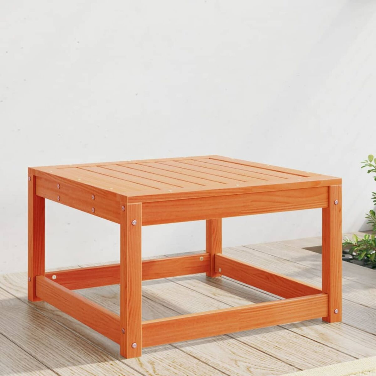 Ein quadratischer, orangefarbener Holztisch mit Lattenrost auf einer Holzterrasse im Freien.