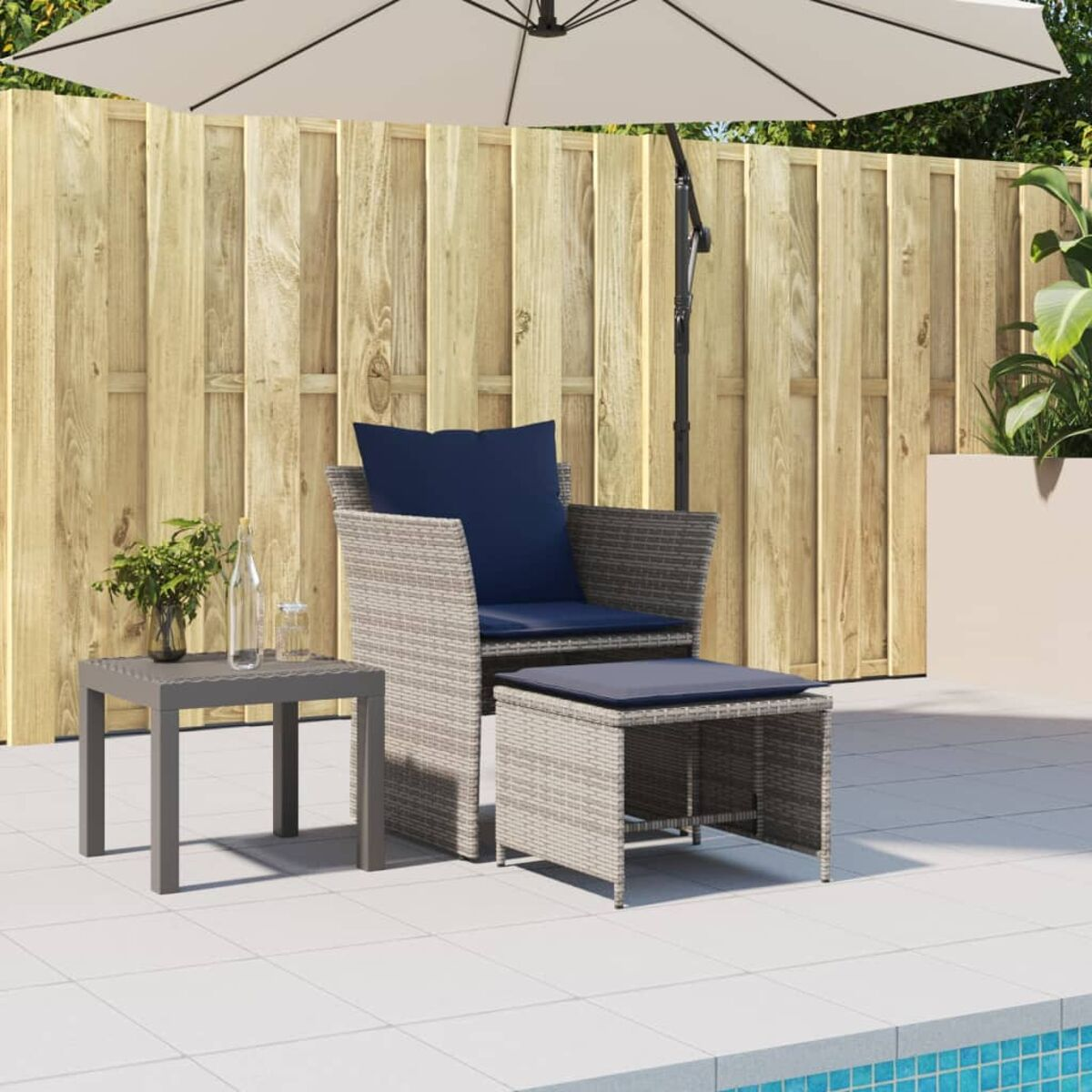 Terrassenset: Stuhl, Ottoman und kleiner Tisch unter einem Sonnenschirm.