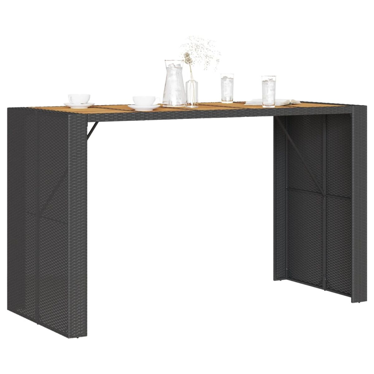 Grauer Rattantisch mit Holzplatte, weißen Tellern, Gläsern und einer Blumenvase.