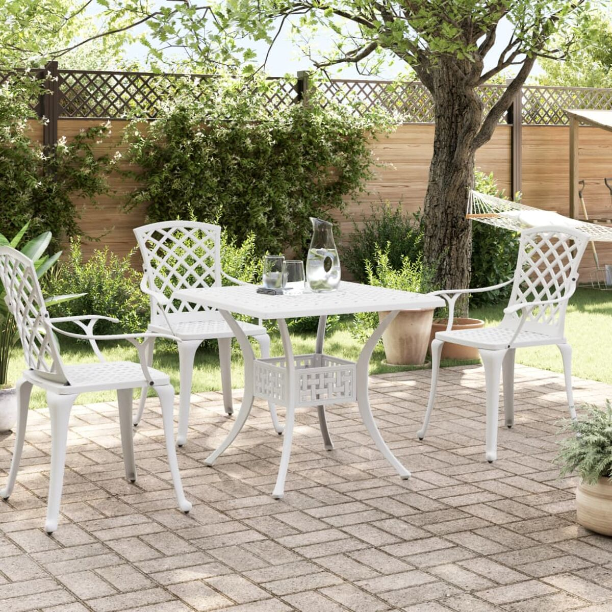 Weißes Ess-Set für den Außenbereich mit Stühlen und einem Tisch auf einer Ziegelterrasse.