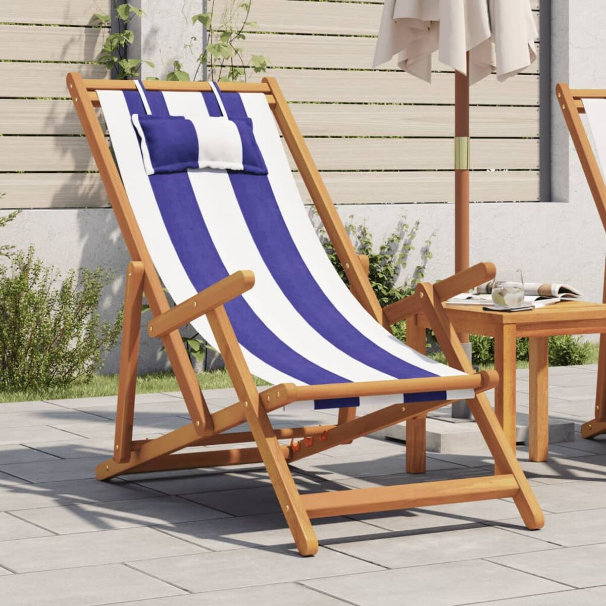 Ein Holz-Deckchair mit blau-weißen Streifen, ein kleiner Tisch und ein weißer Sonnenschirm.