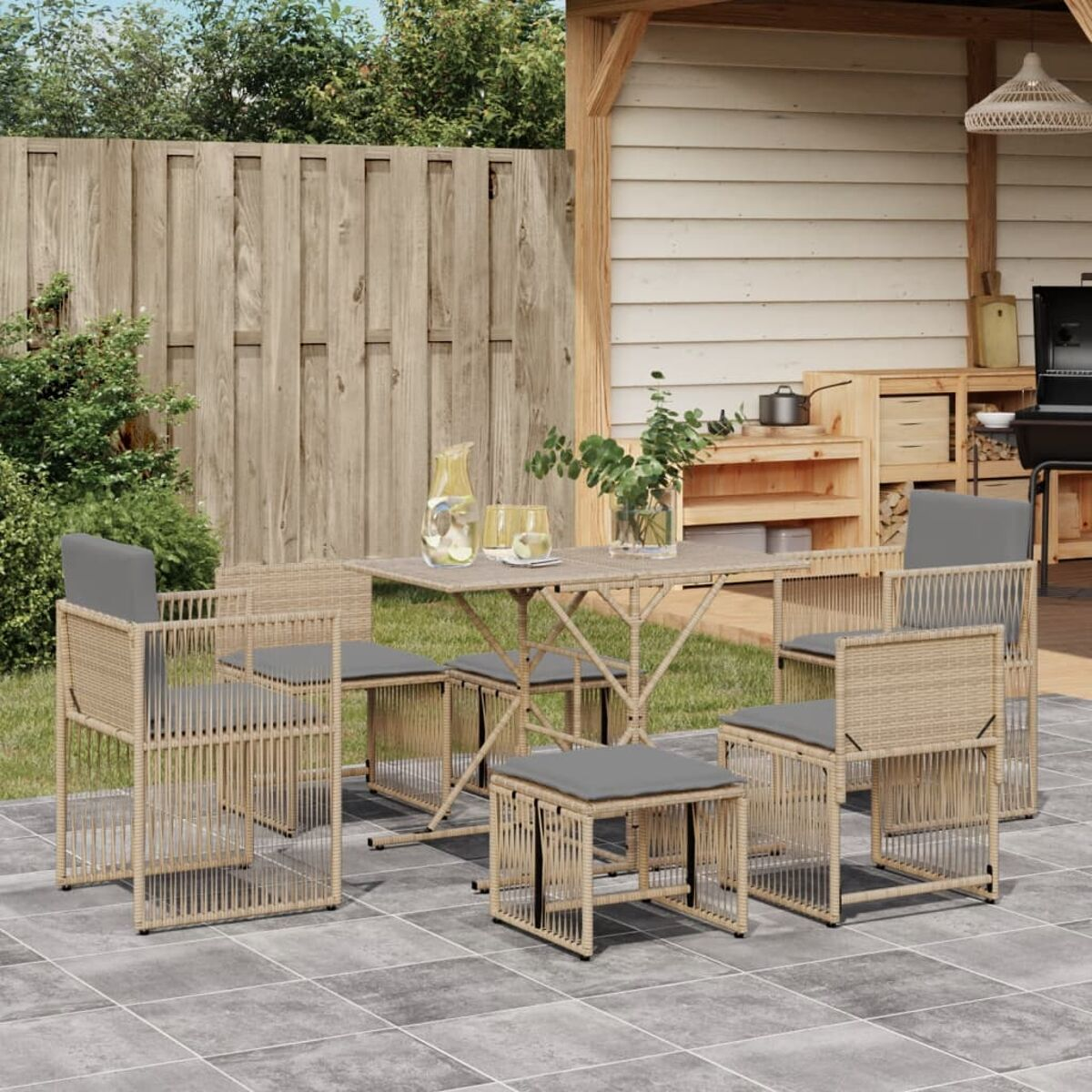 Set da pranzo all'aperto con sedie, tavolo e pouf su un patio.
