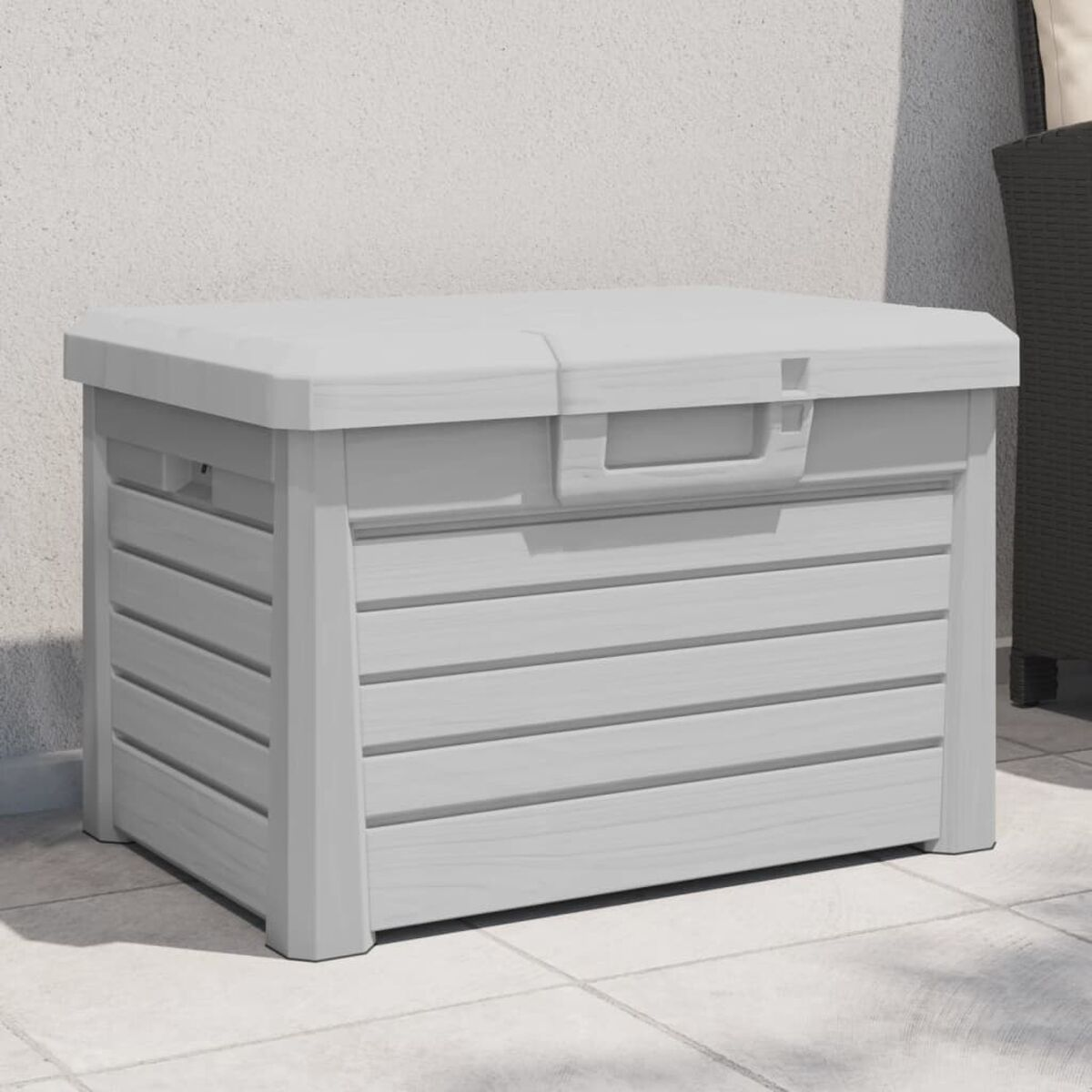 Eine hellgraue Outdoor-Aufbewahrungsbox mit horizontalen Holzlatten auf einer Terrasse.
