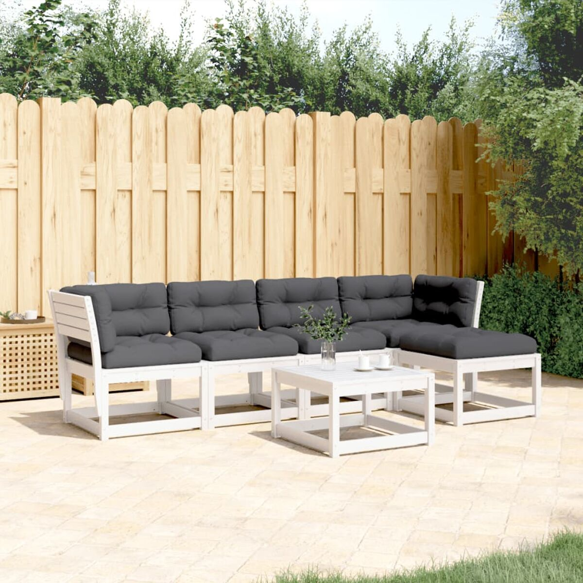 Weißes Outdoor-Ecksofa mit dunkelgrauen Kissen und einem weißen Couchtisch auf der Terrasse.