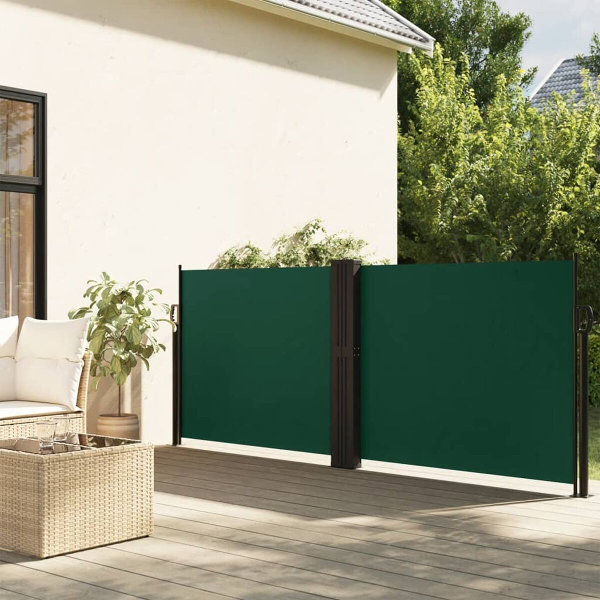 Eine grüne Sichtschutzwand steht neben einem Haus mit weißer Wand.