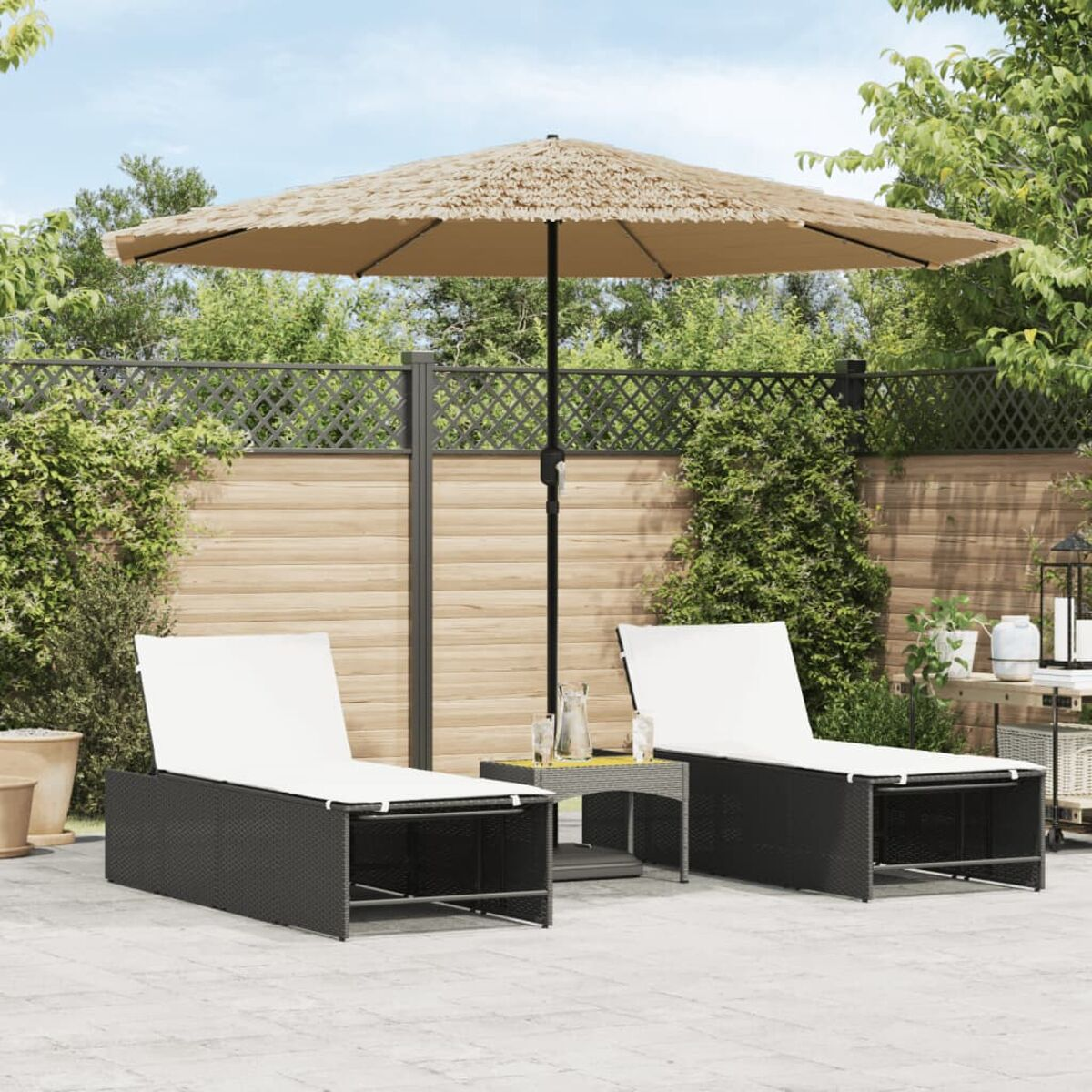 Szene im Freien mit zwei schwarzen Liegestühlen, Sonnenschirm und Tisch.