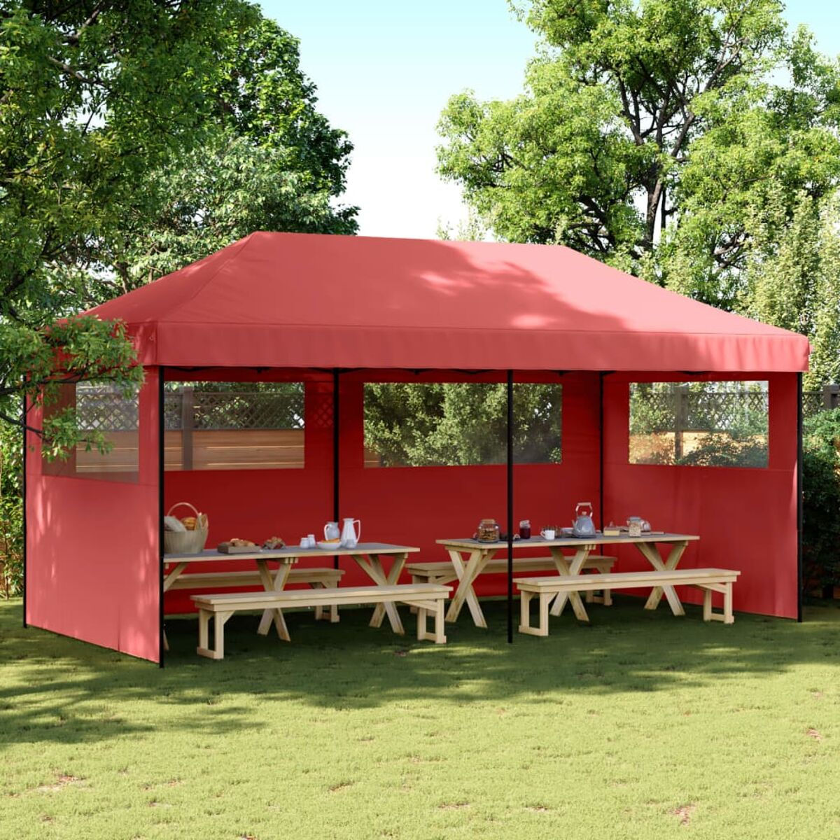 Roter Pavillon mit Tischen und Bänken. Auf grünem Gras unter Bäumen.