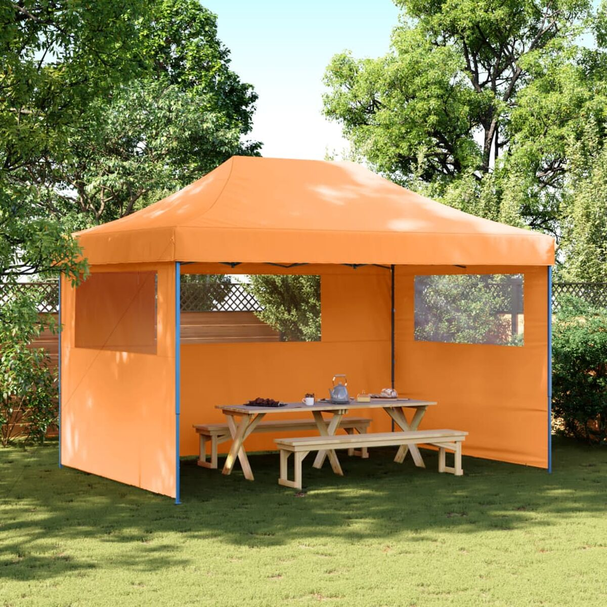 Ein orangefarbener Pavillon mit Tisch, Bänken und Bäumen im Hintergrund an einem sonnigen Tag.