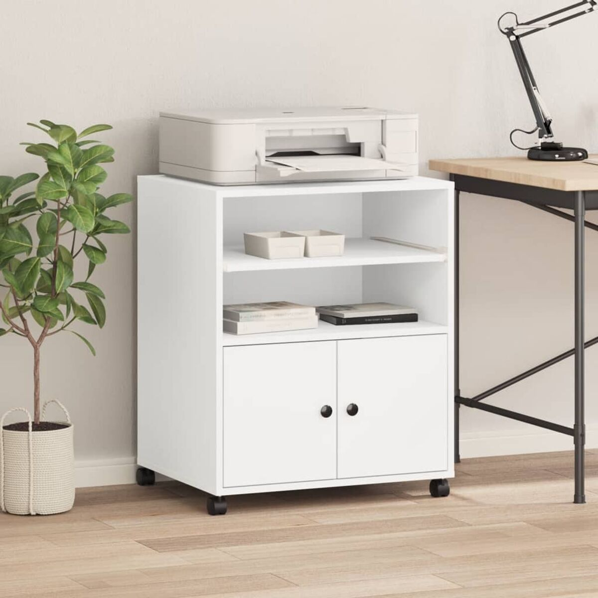 Ein weißer Rollcontainer mit Drucker, Büchern und Büromaterialien, platziert in der Nähe einer Pflanze.