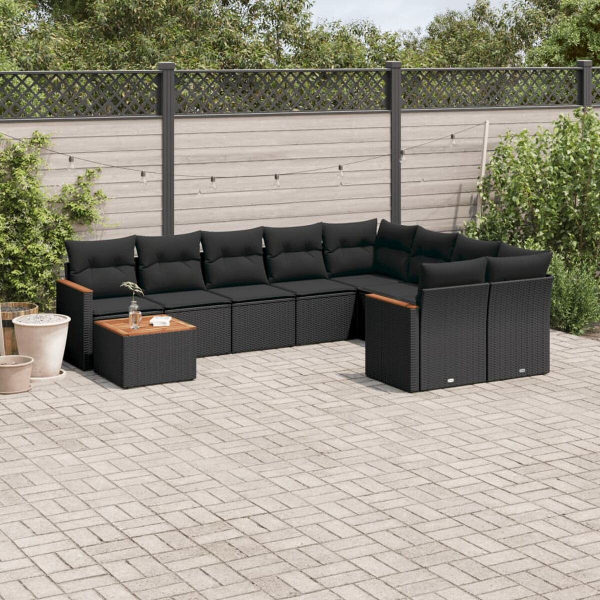 Schwarzes Outdoor-Ecksofa aus Korbgeflecht mit schwarzen Kissen, mit kleinem Tisch.