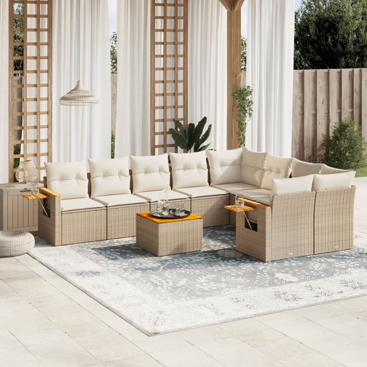 Terrassen-Set mit beigefarbenen Korbsesseln und Kissen, einem Teppich und einem kleinen Tisch.