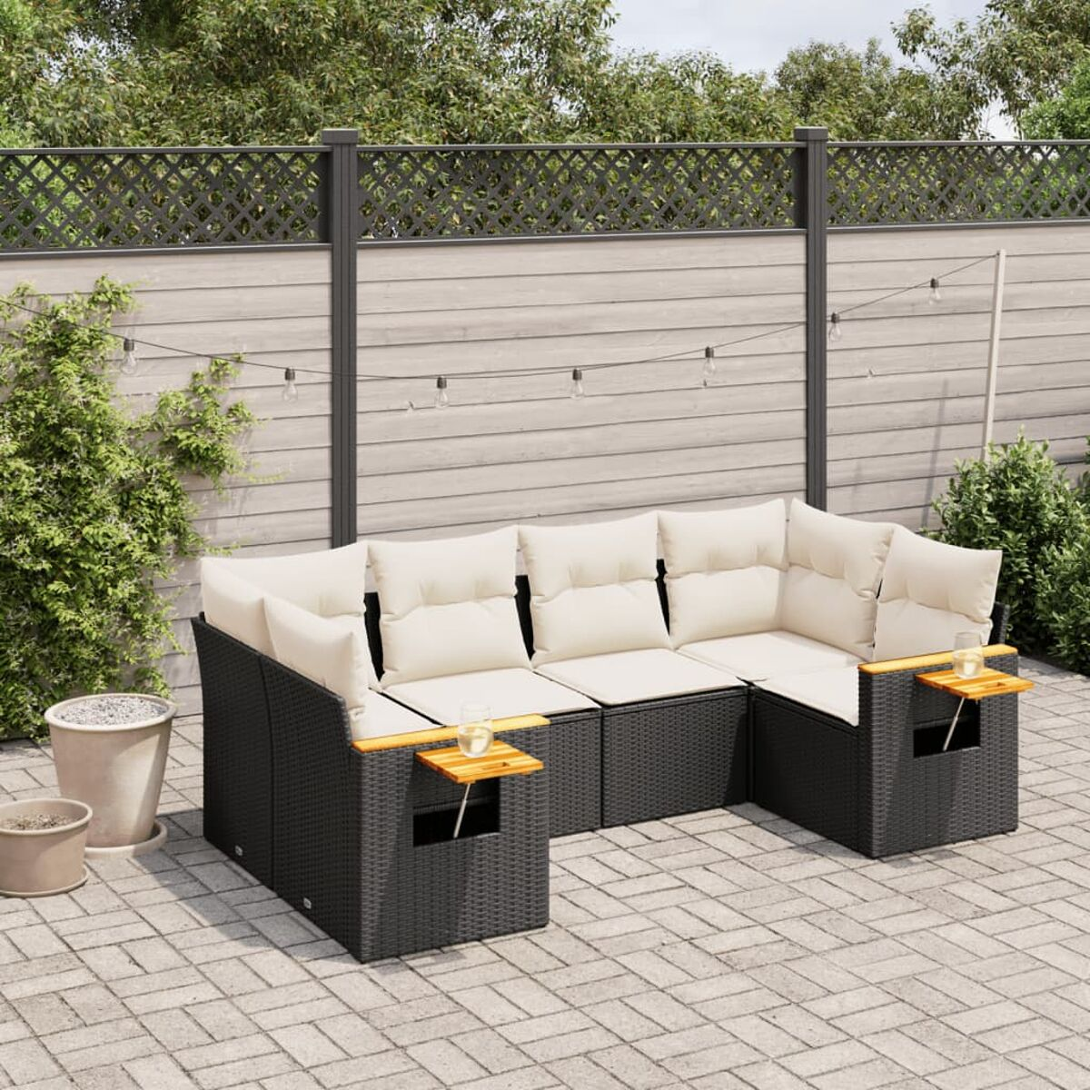 Schwarzes Ecksofa aus Korbgeflecht mit weißen Kissen, Beistelltischen und einer Ziegelterrasse.