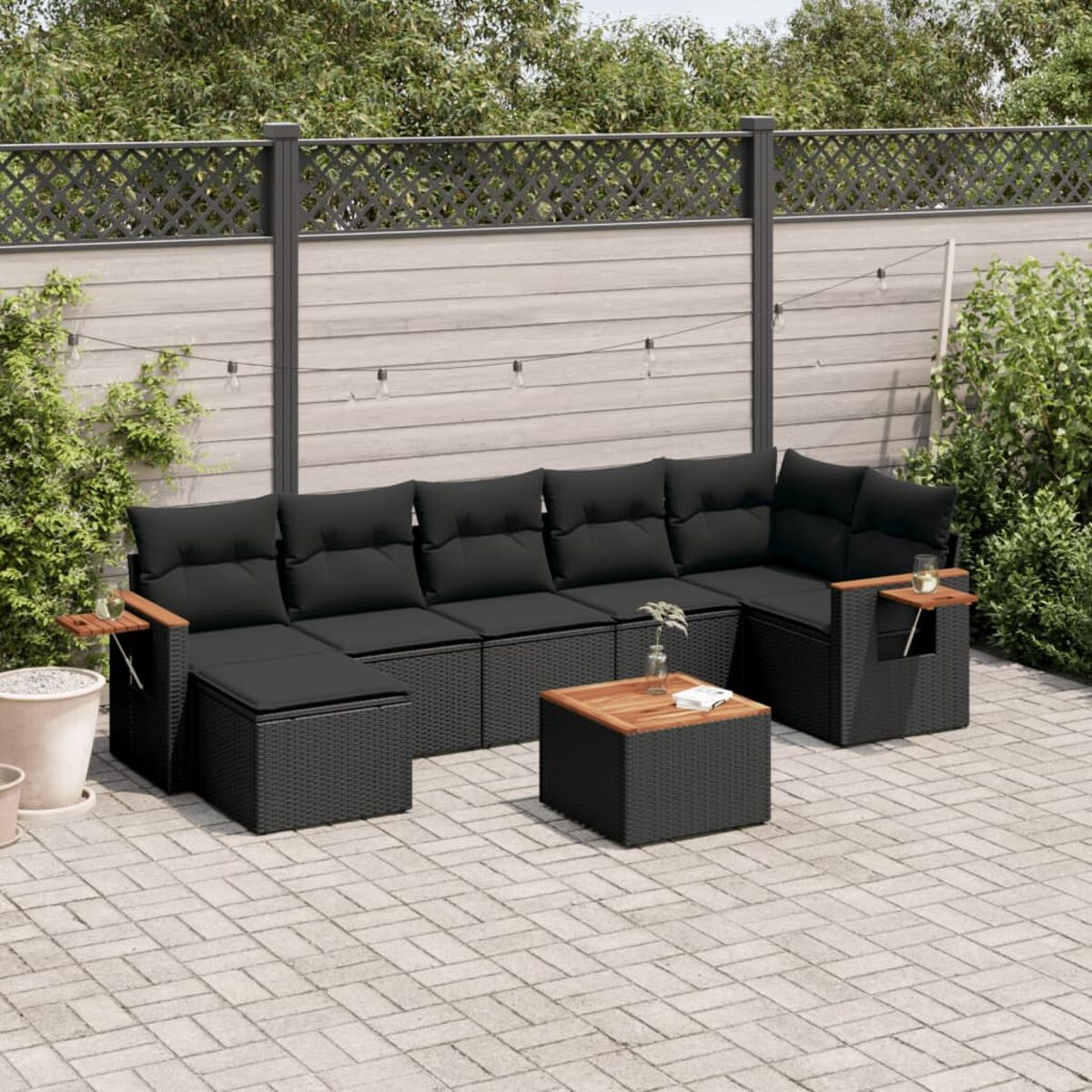 Schwarzes Outdoor-Korbmöbel-Set, Stühle und Tisch auf gepflasterter Terrasse.