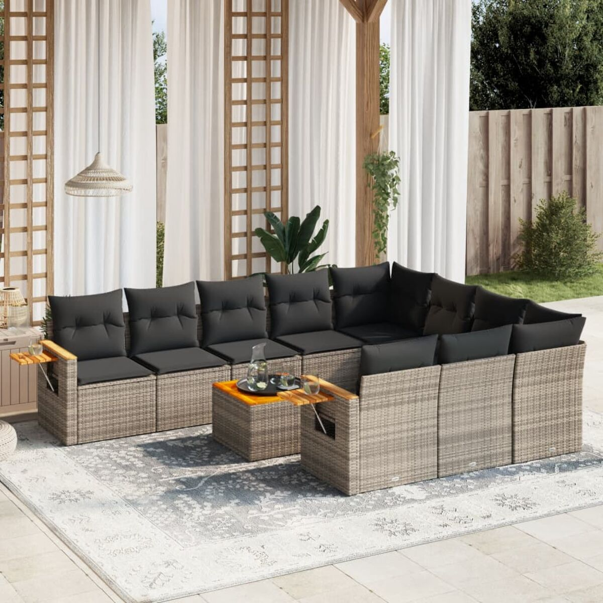 Outdoor-Sofa aus hellbraunem Korbgeflecht mit grauen Kissen, einem Couchtisch und weißen Vorhängen.