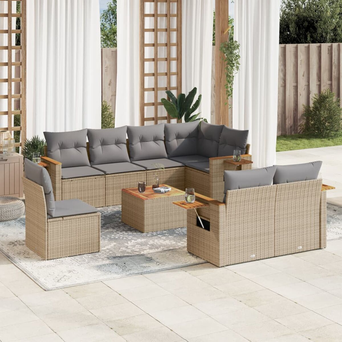 Ein beiges Outdoor-Sitzensemble aus Korbgeflecht mit Kissen, einem Tisch und einem Teppich auf einer Terrasse.