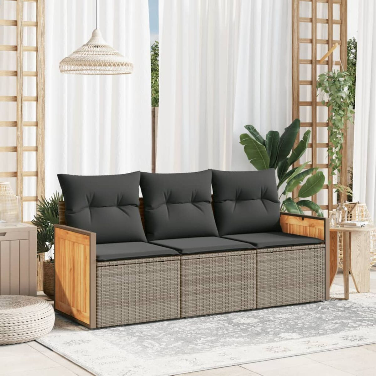 Divano da esterno con cuscini grigi e dettagli in legno. Lo sfondo ha tende, verde e una luce intrecciata.